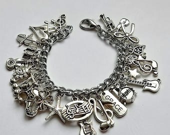 May include: Silver charm bracelet featuring musical instrument charms, including guitars, trumpets, and treble clefs. The bracelet also includes charms of a starfish, a four-leaf clover, and a charm that says "GRACE".