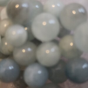 May include: A bowl filled with a collection of smooth, round, light blue and white marbles.