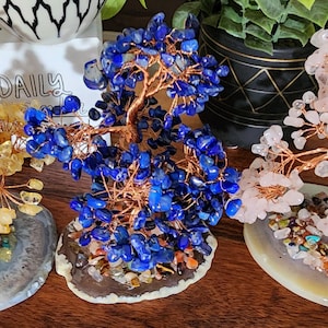May include: Three wire wrapped crystal trees on agate slices. The trees are made with yellow citrine, blue lapis lazuli, and pink rose quartz crystals.