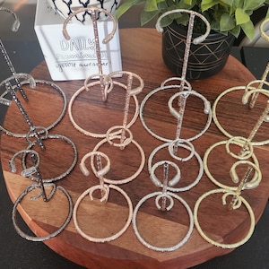 May include: A set of nine gold, silver, and black metal jewelry display stands with rhinestones. Each stand has three tiers of circular rings.