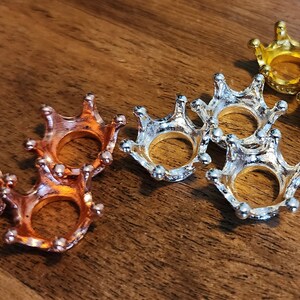 May include: Three gold crown-shaped rings, three silver crown-shaped rings, and three copper crown-shaped rings.