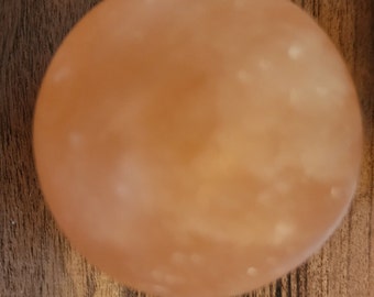 May include: A smooth, round, light orange Himalayan salt lamp with white flecks throughout.