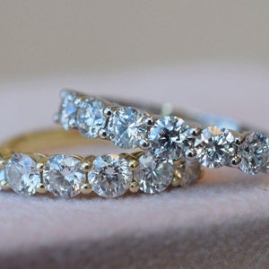May include: Two diamond eternity bands, one in yellow gold and one in white gold, with round brilliant cut diamonds.