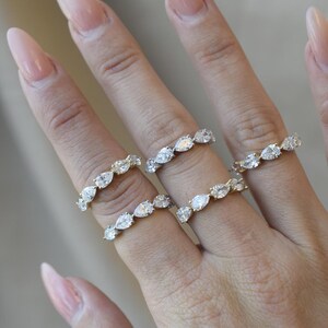 May include: Four gold rings with pear-shaped diamonds set in a continuous line around the band.