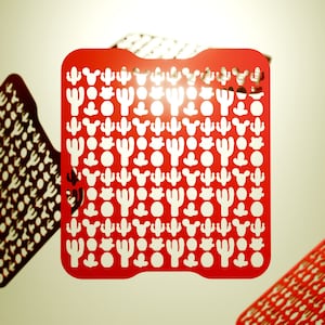 May include: Red plastic stencil with a repeating pattern of cactus silhouettes. The stencil is designed for crafting and decorating projects.