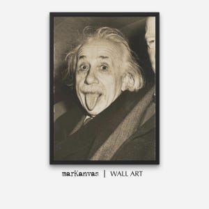 May include: Black and white portrait of Albert Einstein sticking his tongue out. He is wearing a suit and tie. The photo is framed in a black frame.