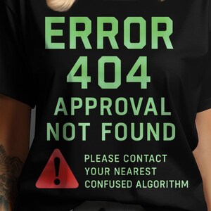 Pode incluir: Camiseta preta com o texto "ERROR 404 APPROVAL NOT FOUND" em letras verdes. Um triângulo de aviso vermelho está abaixo do texto, com as palavras "PLEASE CONTACT YOUR NEAREST CONFUSED ALGORITHM".