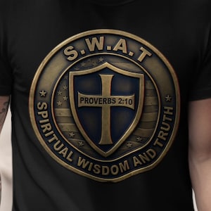 Puede incluir: Camiseta negra con un emblema dorado y azul. El emblema dice "S.W.A.T." y "Spiritual Wisdom and Truth", con una cruz y el texto "Proverbios 2:10". La camiseta es de cuello redondo.