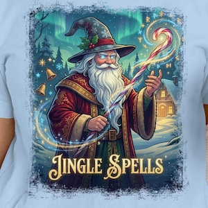 May include: Light blue t-shirt featuring a wizard Santa Claus illustration with the text "Jingle Spells". The wizard wears a red robe and a tall hat. A red and white candy cane is in his hand. A Santa-themed mug is held in the hand.