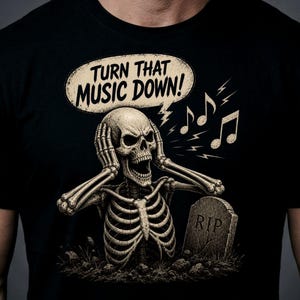 May include: A black t-shirt featuring a graphic of a skeleton emerging from the ground with hands over its ears. A speech bubble above the skeleton reads "TURN THAT MUSIC DOWN!" with musical notes and a tombstone marked "RIP" nearby.