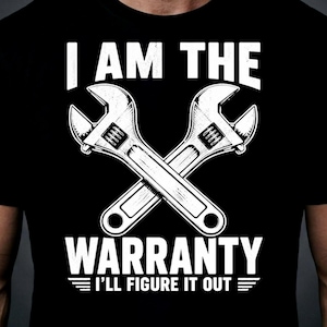 May include: Black t-shirt featuring a white graphic of two crossed wrenches. The text above the wrenches reads "I AM THE" and below reads "WARRANTY I'LL FIGURE IT OUT".