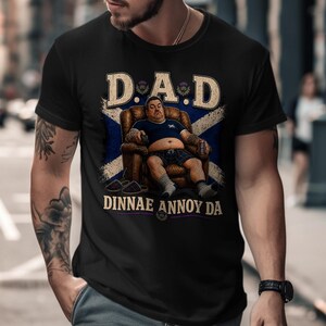 Black t-shirt with "DAD DINNAE ANNOY" text and tartan background.
