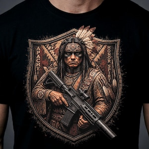 May include: A black t-shirt featuring a graphic print of an Apache warrior wearing a feathered headdress and traditional clothing, holding a black rifle. The design is framed by a shield shape with the text APACHE and HONOR SPIRIT on the sides.
