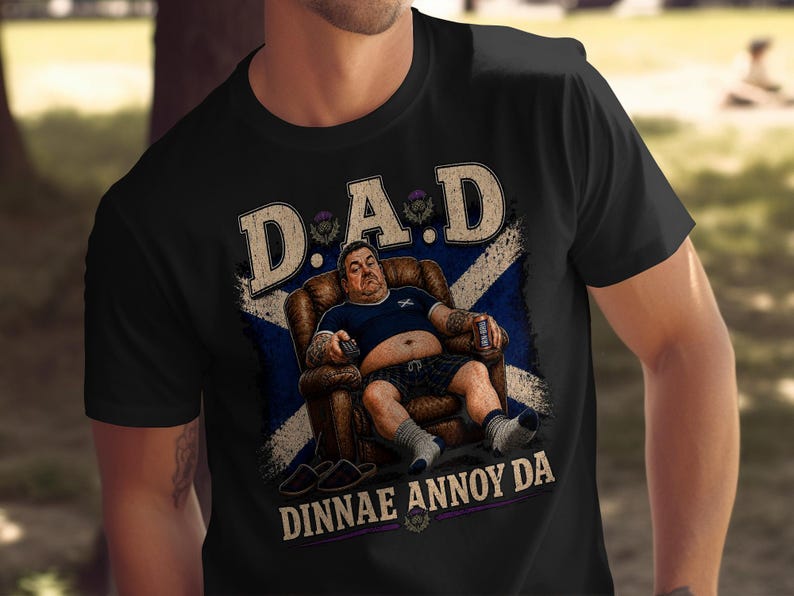 Man in chair wearing black t-shirt with Scottish flag and "DINNAE ANNOY DA" text.
