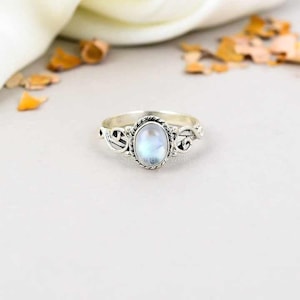 May include: A silver ring featuring an oval iridescent gemstone set in a delicate filigree design.