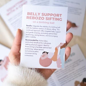 May include: A hand holds a card with text about belly support and rebozo sifting on a birthing ball. The card has a pink header and an illustration of a person on a birthing ball. Other cards are in the background.