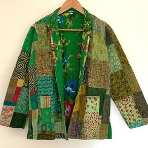 May include: A green quilted jacket with a patchwork design. The jacket has a floral print lining and a button closure.