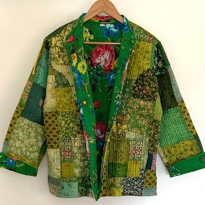 Può includere: Una giacca trapuntata verde con fodera a stampa floreale. La giacca è realizzata in tessuto patchwork con diversi motivi e colori.