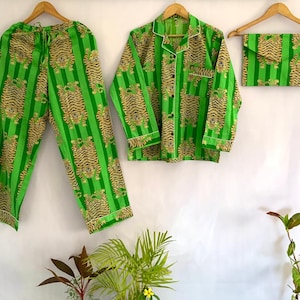 May include: A green pajama set with a tiger print. The set includes a long-sleeved button-down shirt, pants, and a small pouch. The pajamas have a vertical green stripe pattern with tiger illustrations. The edges of the shirt and pants are trimmed with white.