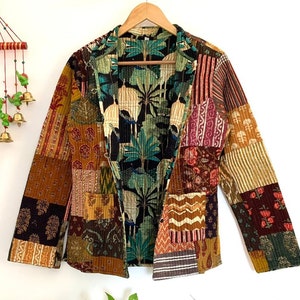 May include: A patchwork blazer in various patterns and colours, including floral, paisley, and striped designs. The interior lining features a tropical bird and foliage print. The jacket is hanging on a wooden hanger.