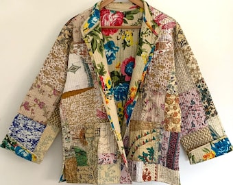 Puede incluir: Una chaqueta acolchada de retazos con forro de estampado floral. La chaqueta está hecha de varias telas en tonos beige, marrón y blanco. El forro de estampado floral es en tonos rosa, azul y amarillo.