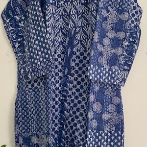 May include: A long, blue and white patterned robe with a V-neck. The robe features a patchwork design with various geometric and floral patterns. The robe is approximately 60 inches long and is made of a soft, quilted fabric.