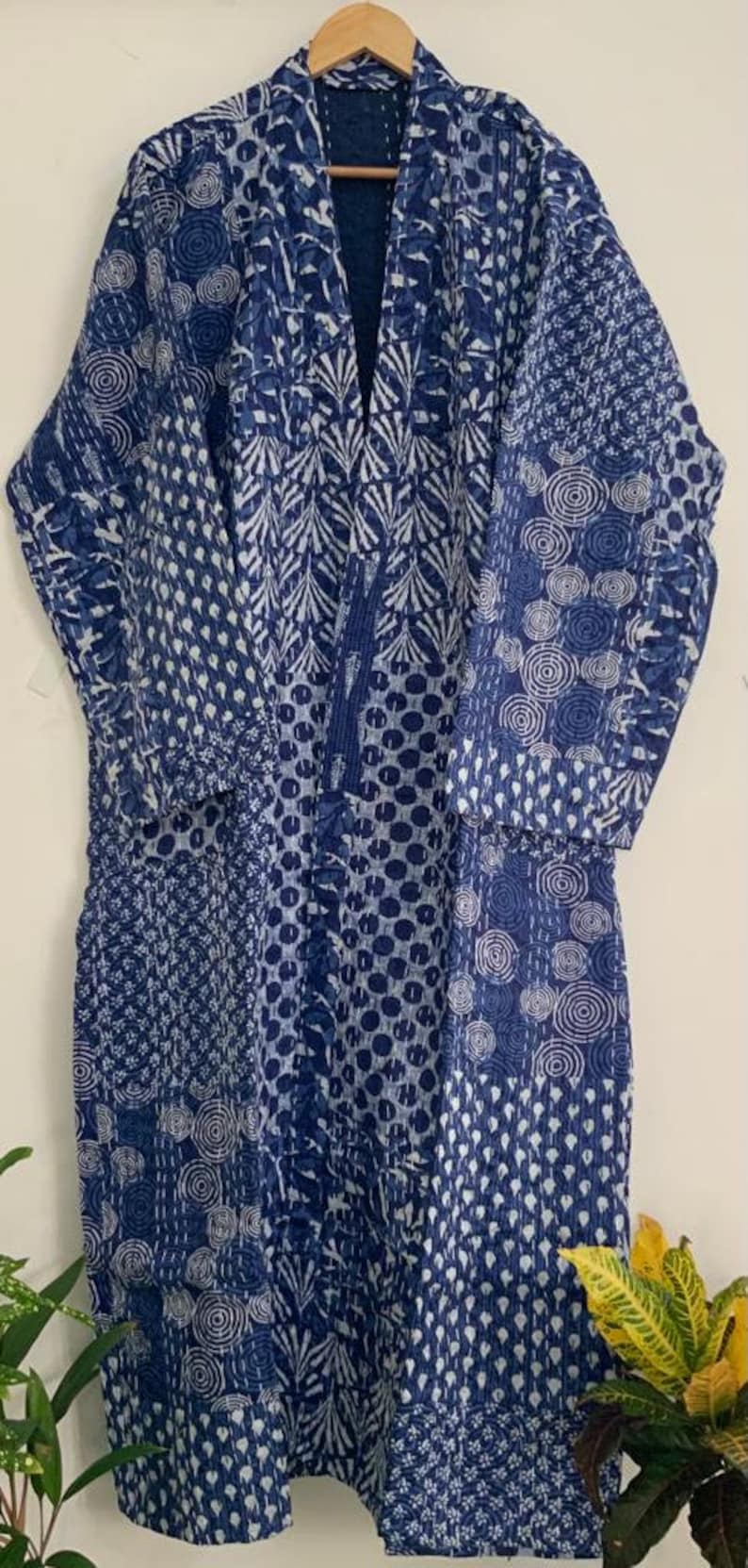 May include: A long, blue and white patterned robe with a V-neck. The robe features a patchwork design with various geometric and floral patterns. The robe is approximately 60 inches long and is made of a soft, quilted fabric.