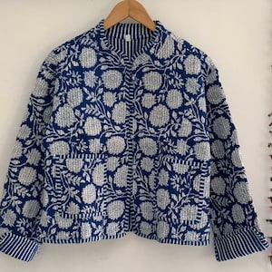 Peut inclure: Une veste matelassée à imprimé floral bleu et blanc avec un col mandarin et des manches longues. La veste a une fermeture boutonnée et une poche de chaque côté.