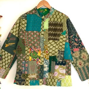 May include: A green, blue and brown patchwork quilted jacket with a mandarin collar and button closure. The jacket has a unique, hand-stitched design and is made from recycled fabrics.