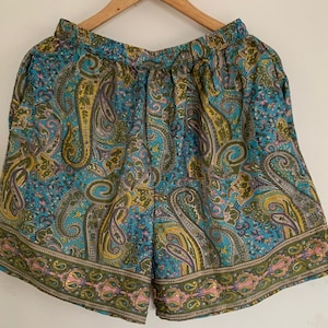 Könnte beinhalten: Blaue und grüne Shorts mit Paisley-Muster, Kordelzug und dekorativem Saum.