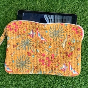 May include: A yellow laptop sleeve with a floral pattern. The sleeve has a zipper closure and is made of quilted fabric.