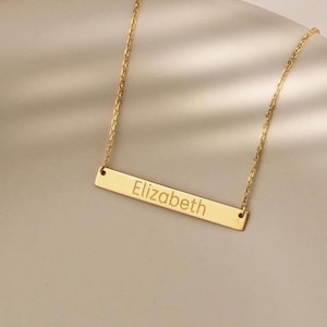 May include: A gold bar necklace with the name "Elizabeth" engraved on it.