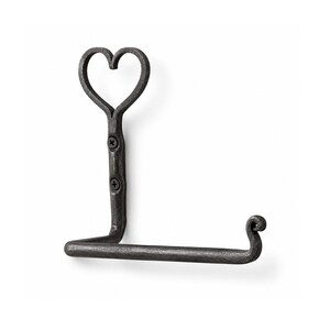 May include: A wrought iron toilet paper holder with a heart-shaped top. The holder is dark gray and features a decorative scroll at the end of the horizontal bar. The holder is mounted with two screws.