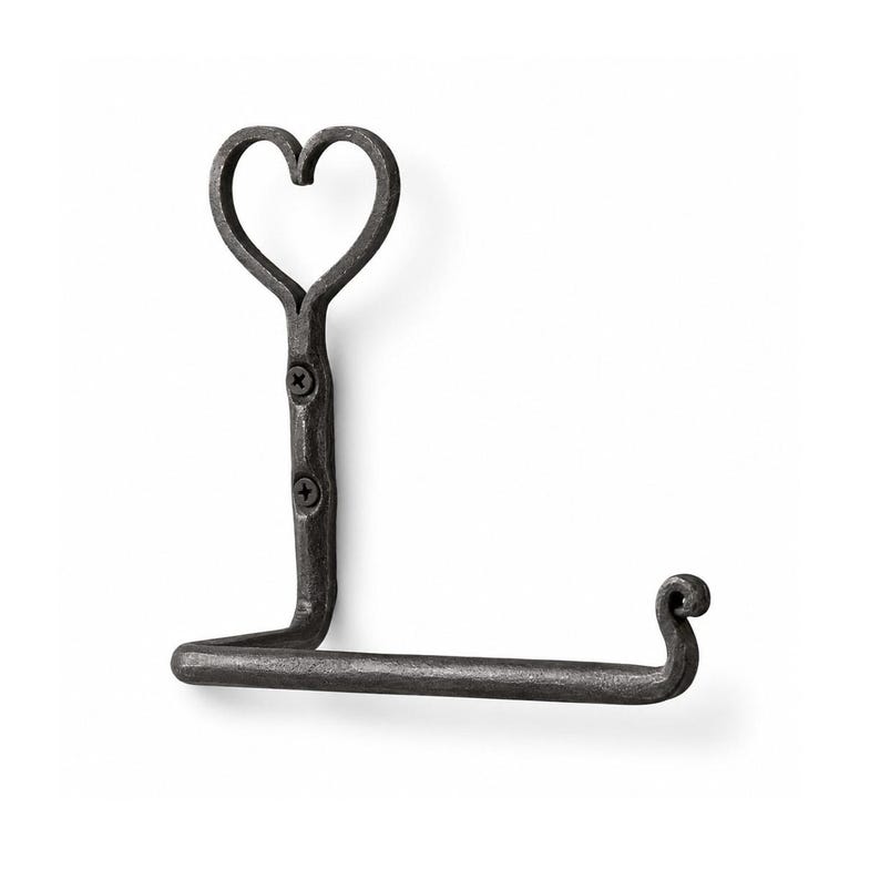 May include: A wrought iron toilet paper holder with a heart-shaped top. The holder is dark gray and features a decorative scroll at the end of the horizontal bar. The holder is mounted with two screws.