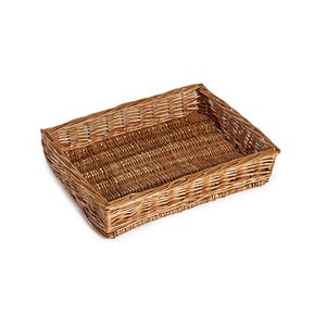 May include: A rectangular wicker basket with an open top. The basket is made from light brown woven reeds, creating a textured appearance. The sides slope gently, and the empty basket sits against a white backdrop.