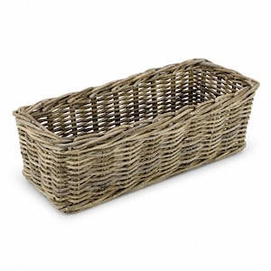 May include: A rectangular wicker basket in a natural, neutral tone. The basket is constructed from interwoven, thin, light brown branches, creating a textured surface. The basket's shape is long and narrow, suitable for storage or display, approximately 30cm in length.