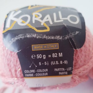 May include: A ball of pink yarn with a label that reads "KORALLO" and "MADE IN ITALY." The label also indicates the yarn weight is 50 grams and the needle size is U.S. 8-9.