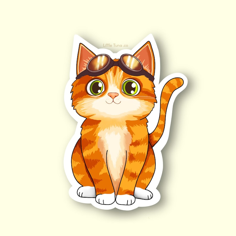 May include: A cartoon sticker of a ginger cat wearing brown goggles. The cat has green eyes, white paws, and a white chest. The sticker has a white border and the text "Little Tuna .co" is visible at the top.