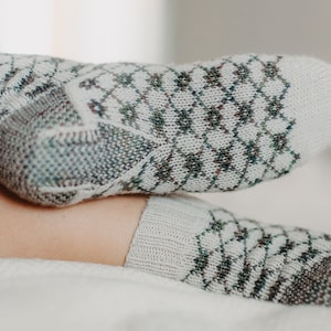 May include: A pair of white socks with a green and brown diamond pattern. The socks are made of a soft, knitted fabric.