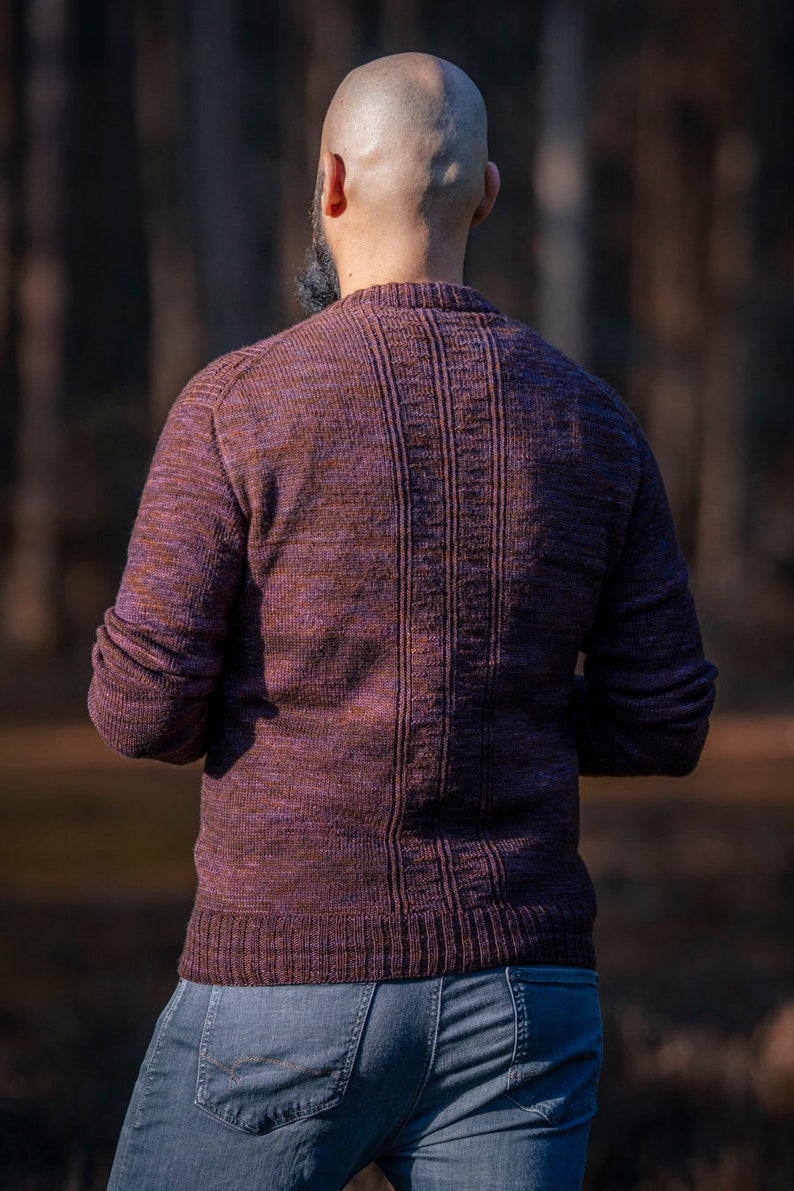 May include: A person wearing a purple and brown sweater with a ribbed texture. The sweater has a crew neck and long sleeves.
