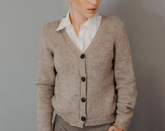 May include: A light brown cardigan with a v-neck and button closure. The cardigan is made of a soft, knitted fabric and has long sleeves.