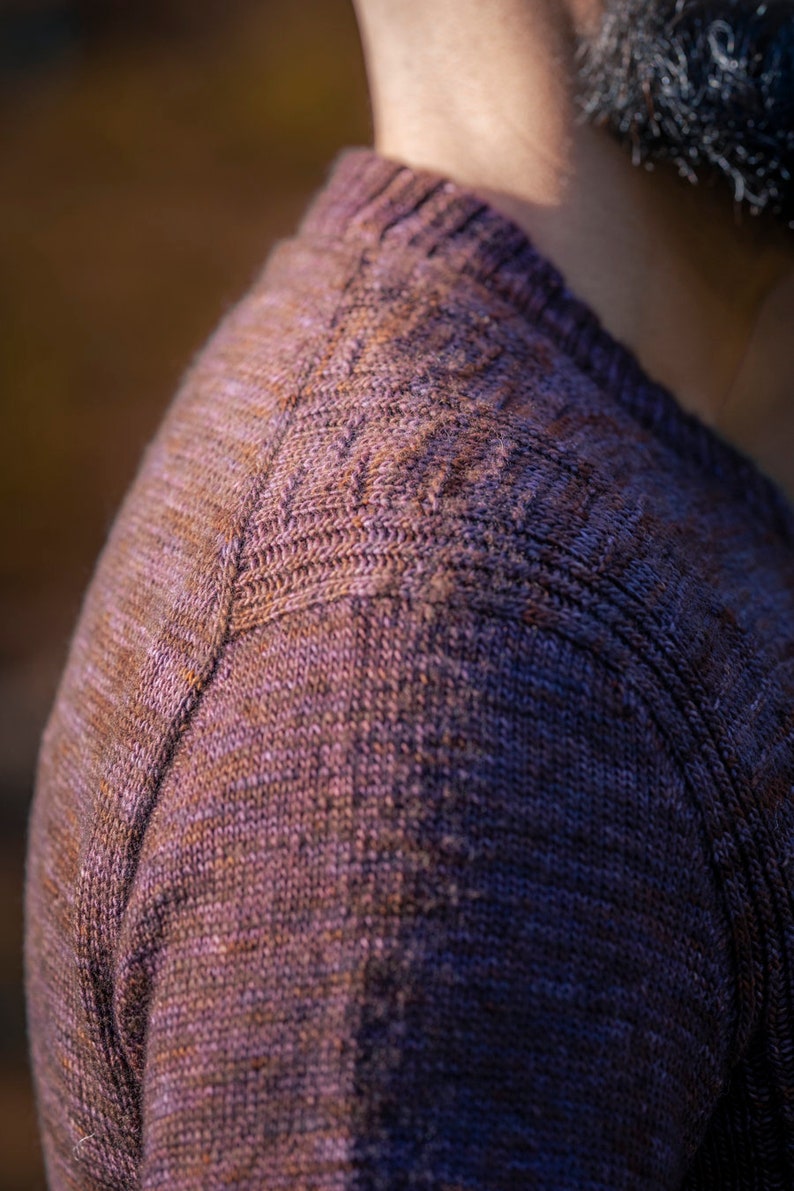 May include: Close-up of a brown knitted sweater with a textured pattern. The sweater is made of a soft, comfortable material.