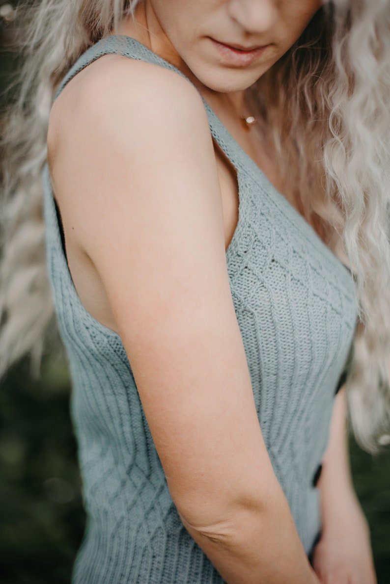 Peut inclure: Gros plan sur le bras d'une femme portant un haut sans manches en tricot bleu clair. Le haut a une texture c&ocirc;tel&eacute;e et un motif d&eacute;licat.