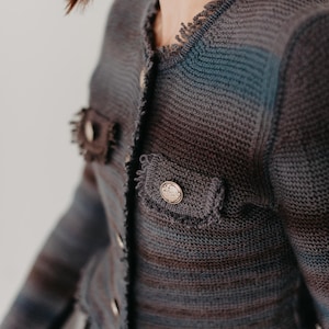 May include: A dark blue and gray striped knitted cardigan with a frayed edge and gold button accents.