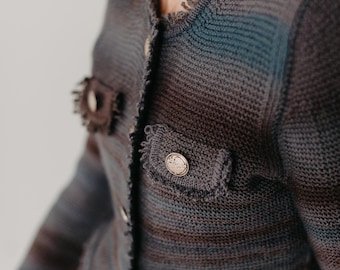 May include: A dark blue and gray striped knitted cardigan with a frayed edge and gold button accents.