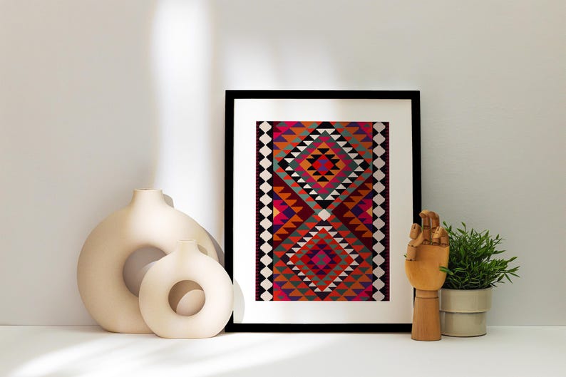 May include: A framed print of a colorful geometric pattern in shades of red, orange, pink, green, and black. The print is set against a white wall with two decorative ceramic vases and a wooden hand sculpture.