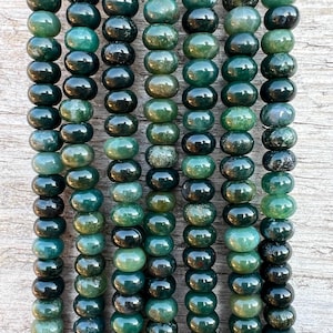 Può includere: Una collana di perline di agata verde scuro e verde chiaro. Le perline sono rotonde e hanno una finitura liscia e lucida.