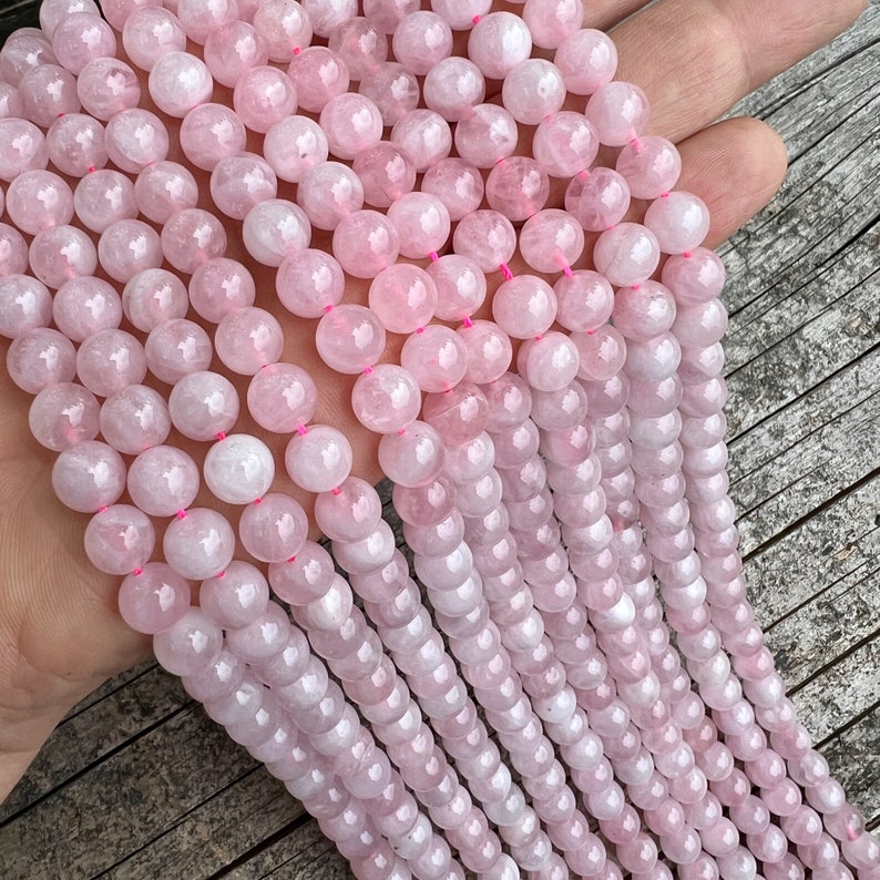 Madagascar rose quartz beads strands held in hand on top of a trunk