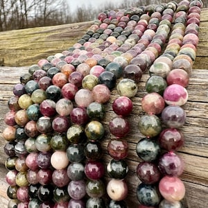 Tourmaline stone beads strands hanging over a bright wood board at outdoors and pictured under natural day light