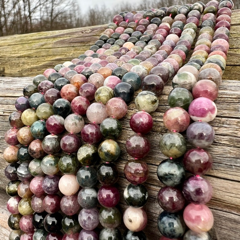 Tourmaline stone beads strands hanging over a bright wood board at outdoors and pictured under natural day light